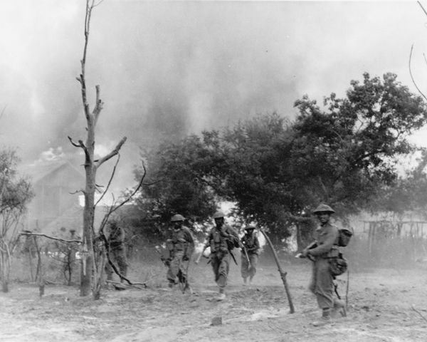 Indian infantry advance through a burning village, Burma, 1945 