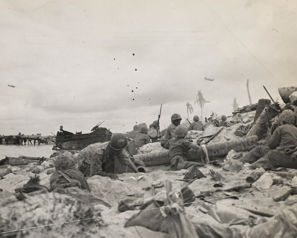 US Marines take cover on a beach as dive-bombers fly overhead, Okinawa, April 1945 