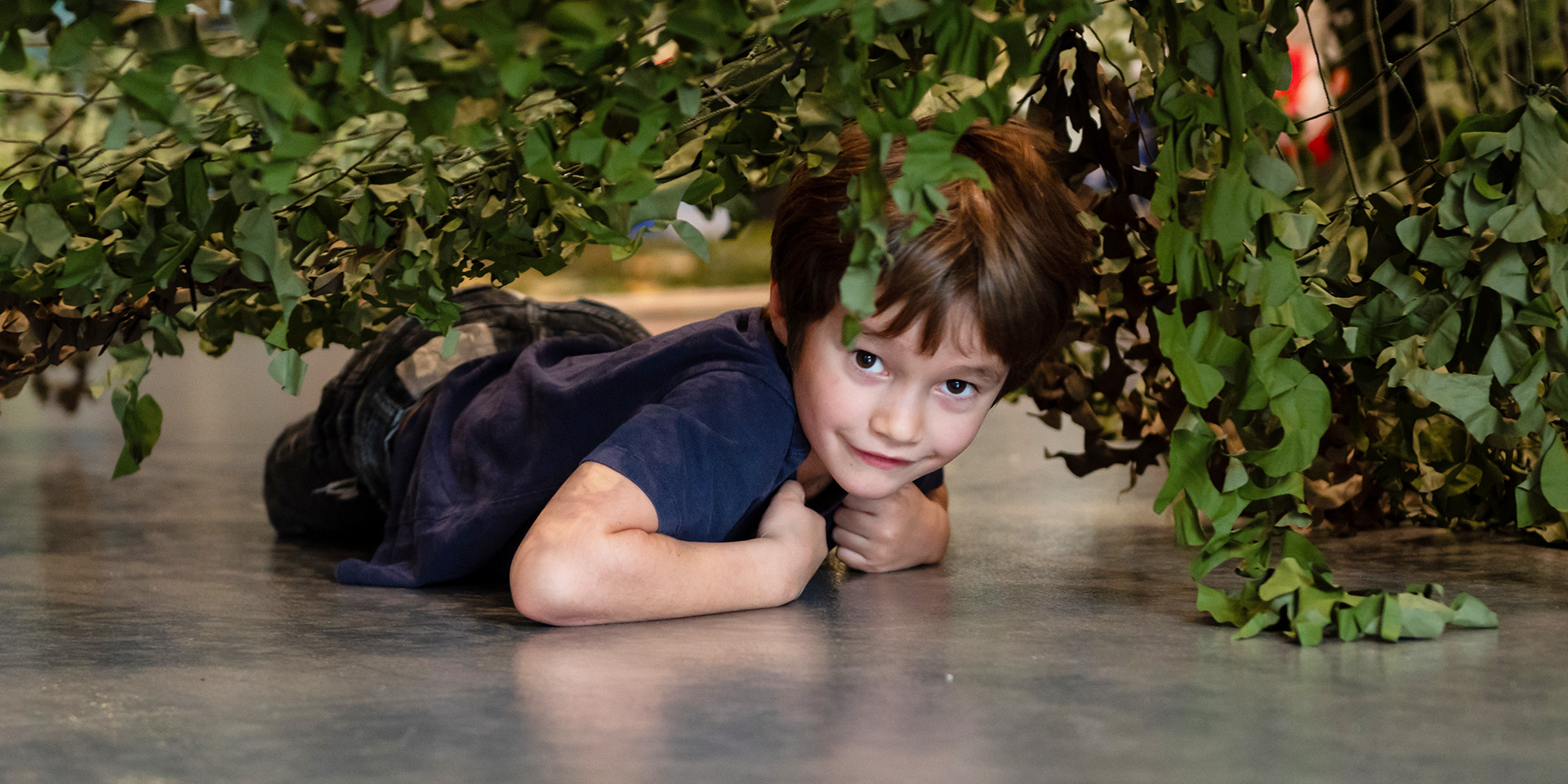 A child crawling under a camouflage net