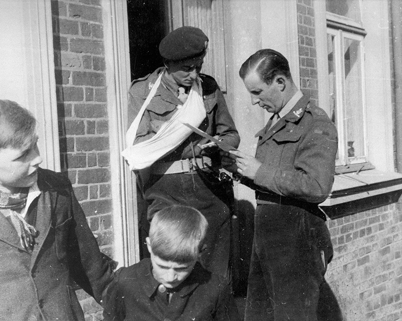 Officers of the 15th/19th King’s Royal Hussars reading the classified 'End of the War in Europe' message, Germany, 7 May 1945