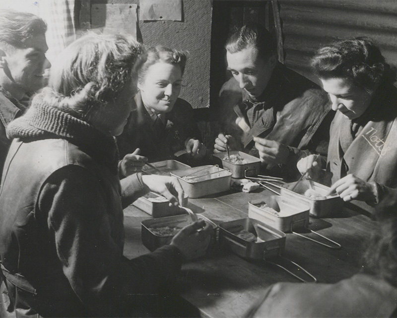 A mixed heavy anti-aircraft unit enjoy a meal inside a Nissen hut