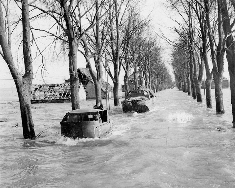 An M29 Weasel and a DUKW amphibious truck in a flooded avenue, near Nijmegen in the Netherlands, 15 February 1945