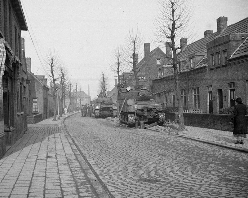 Sherman tanks parked up in a Dutch town prior to a new deployment, February 1945