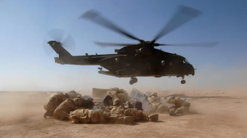 Soldiers huddle under helicopter