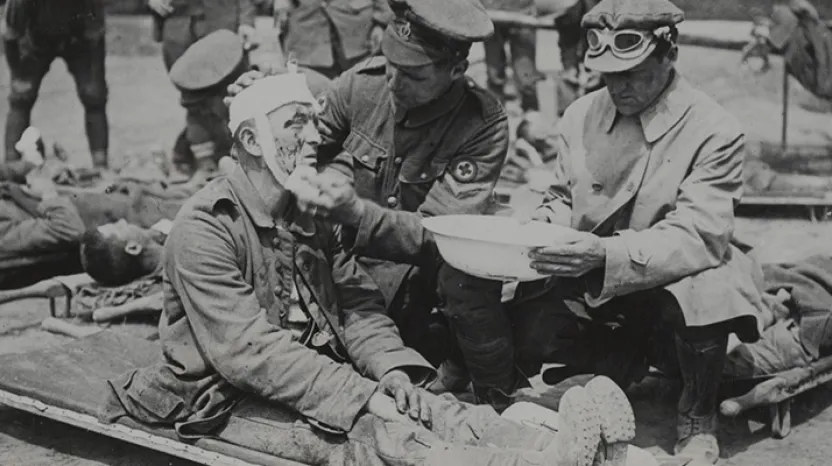 A British medical orderly treats a wounded German soldier, c1916