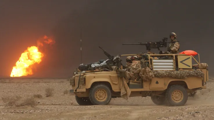 A Royal Irish Regiment vehicle passes a burning oil well during the invasion of Iraq, March 2003