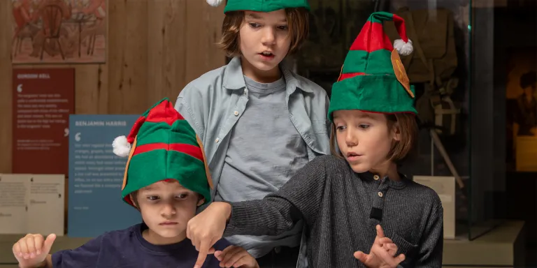 Children exploring a gallery wearing festive hats