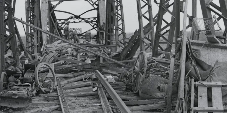 Abandoned weapons and vehicles cover a railway bridge over the River Reno, Italy, April 1945